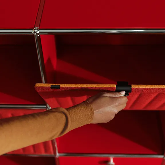 Detailaufnahme eines USM Haller Soft Panels. Eine Hand klappt das Panel auf, die Innenseite ist Orange, die Außenseite ist Rot.